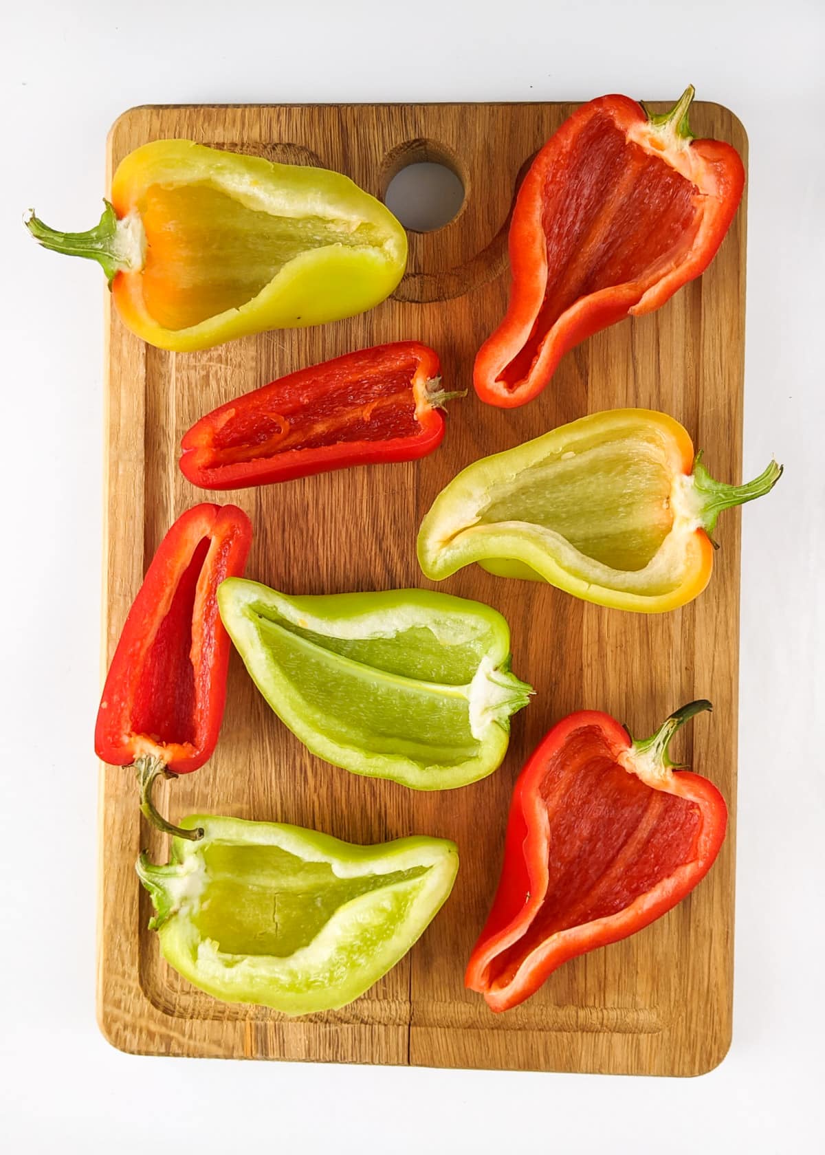 Cleaned bell pepper boats on a wooden cut board.
