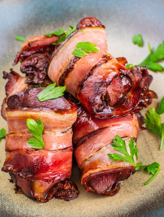 Close look of bacon wrapped turkey livers with copped parsley on a plate.