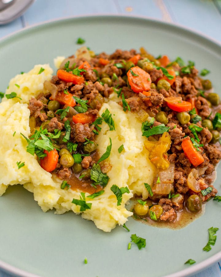 Smashed potatoes with grounded meat on a plate.