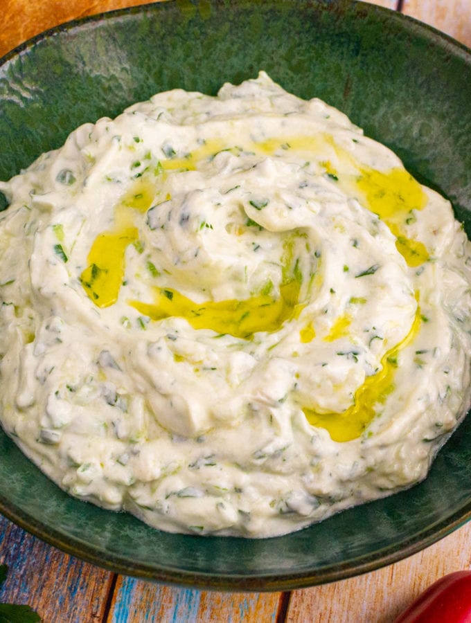 Close look of a green plate with Greek tzatziki sauce with olive oil