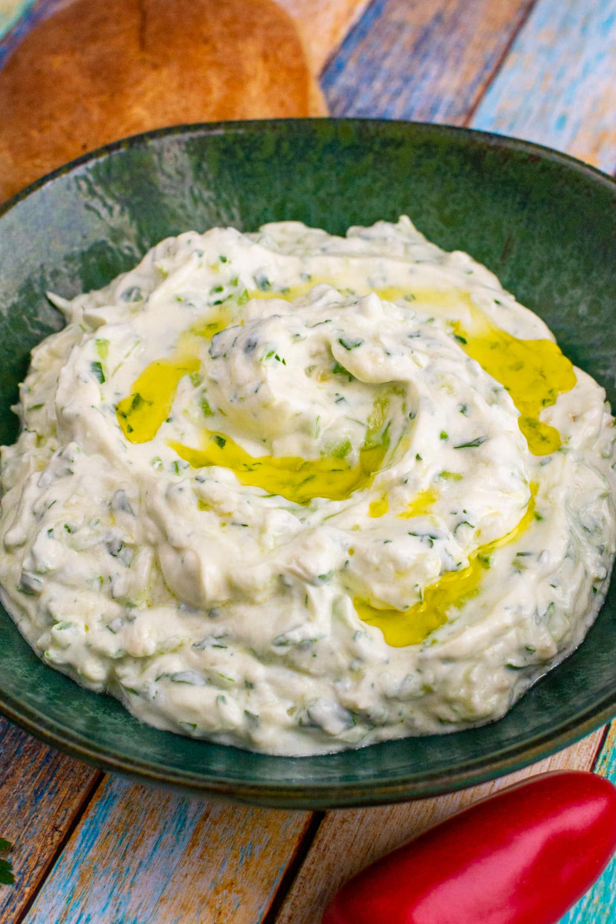 A green plate with tzatziki sauce in a green plate on a wooden table.