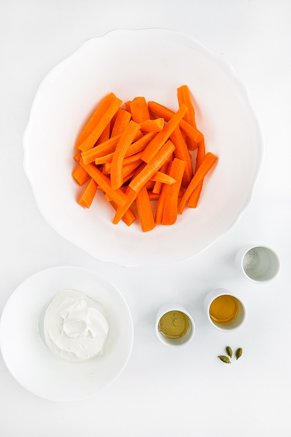 Sliced carrots with yogurt and spices on white table.