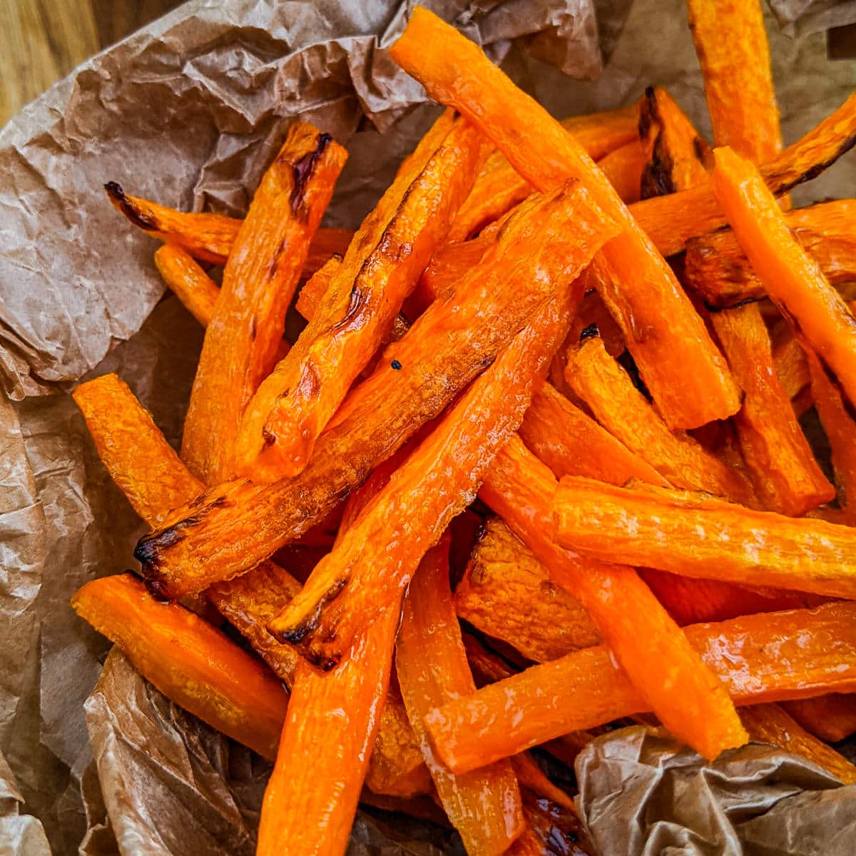 Close view of fried carrot sticks on a perchment paper.
