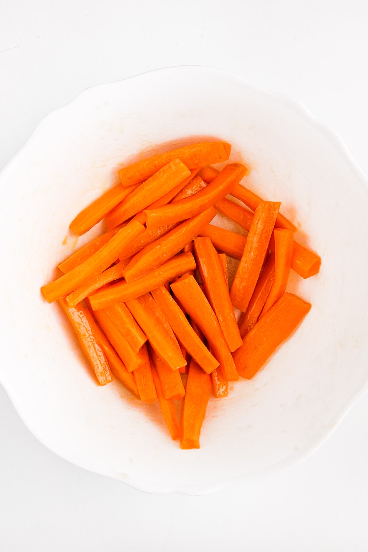 Carrot fries sprayed with oil in a white plate.