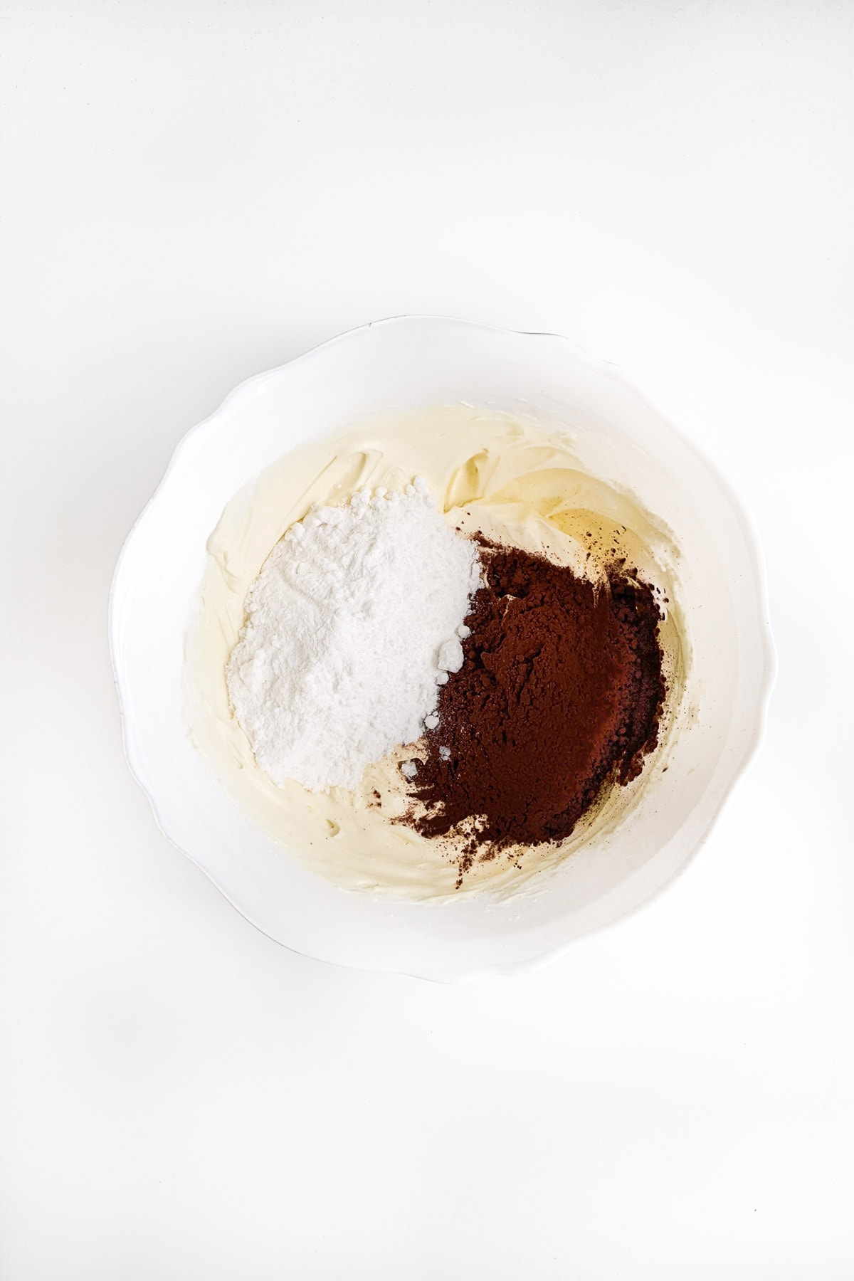 A white plate with whipped cream with sugar and cacao.
