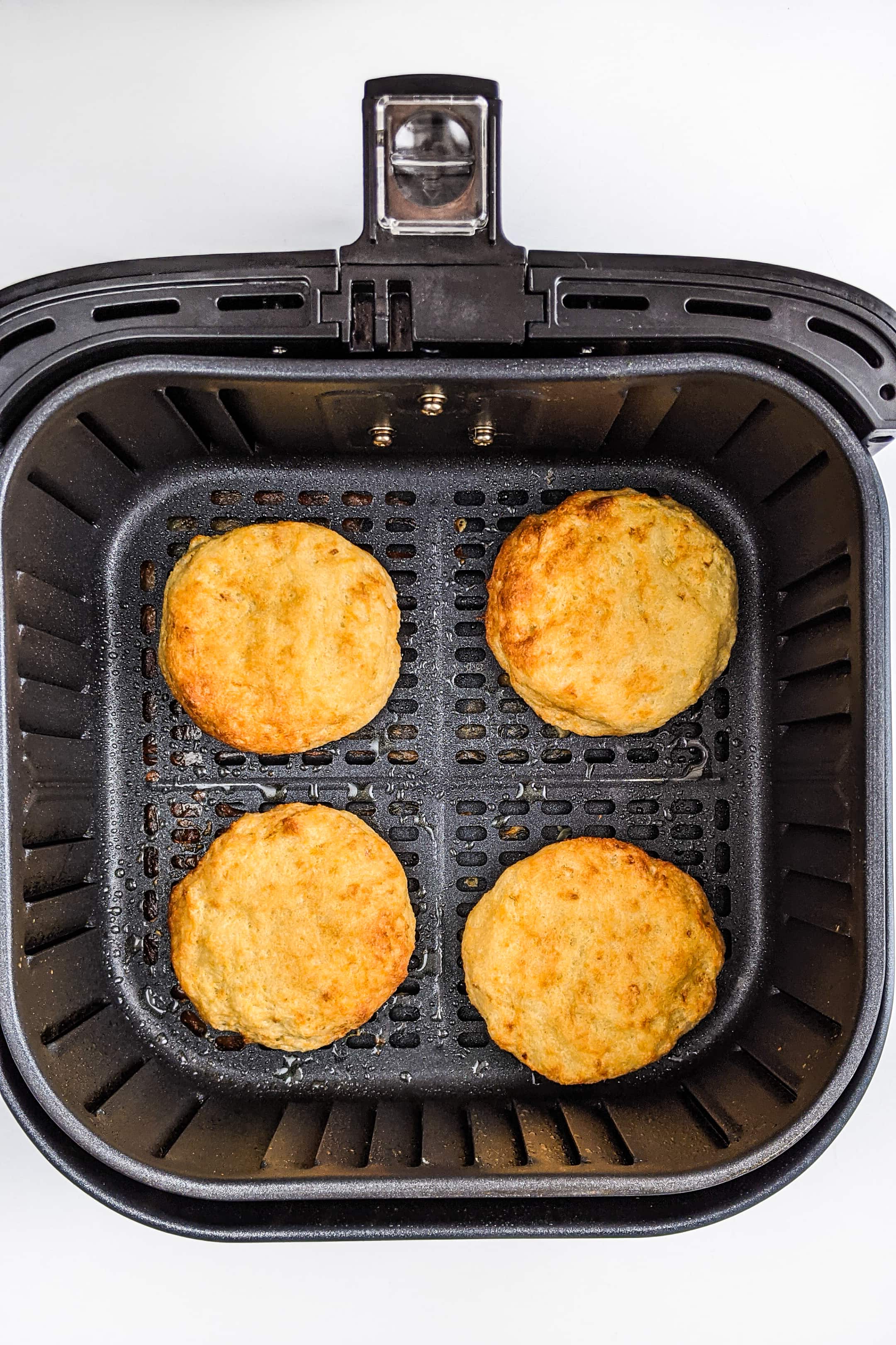 Top look of air fried hash brown patties in an air fryer basket.