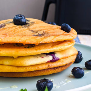 Perfect homemade air fryer pancakes with blueberries, honey and mint on a plate.