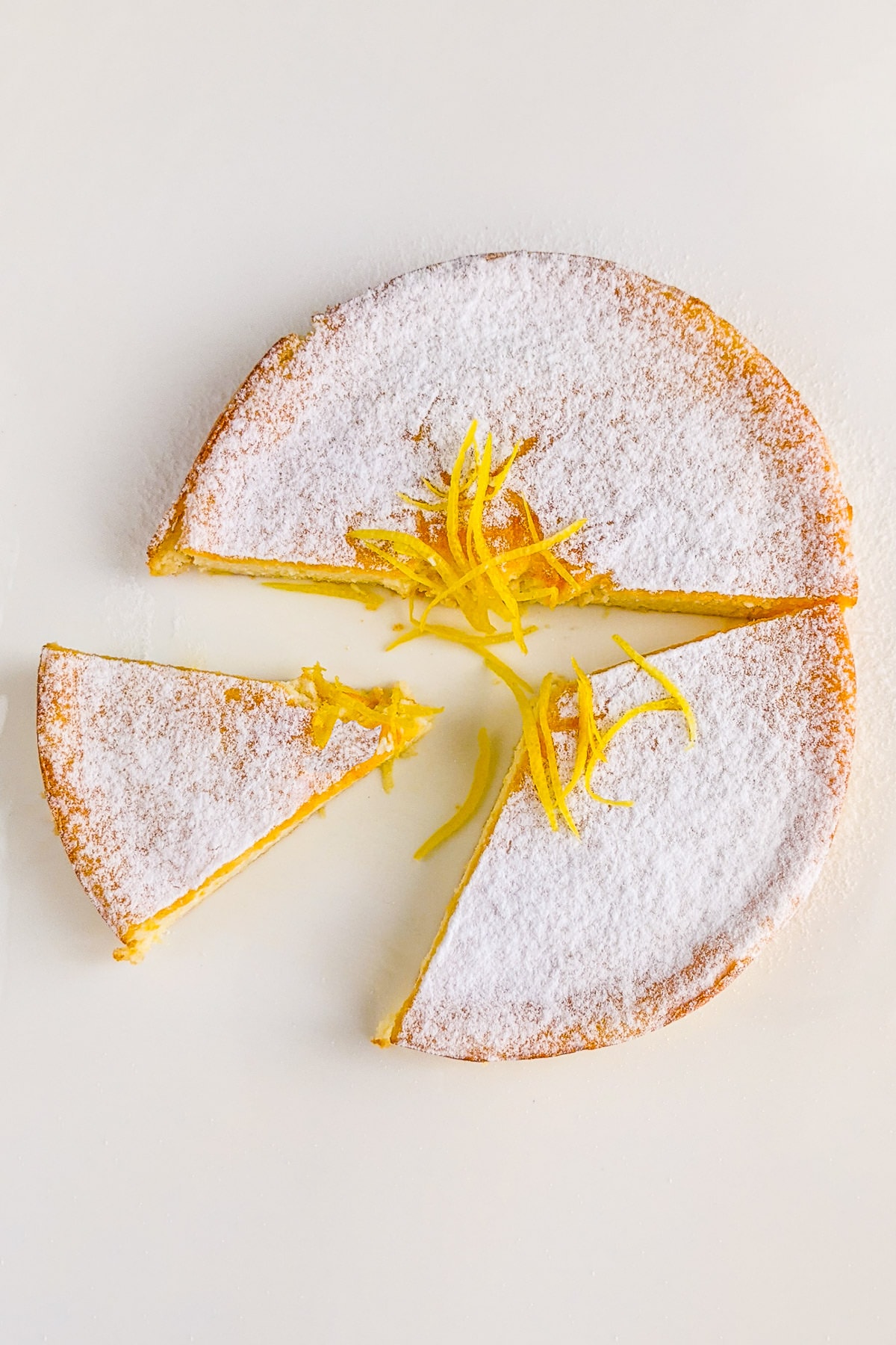 Top view of Ricotta Cheesecake powdered with sugar and lemon peel slices.