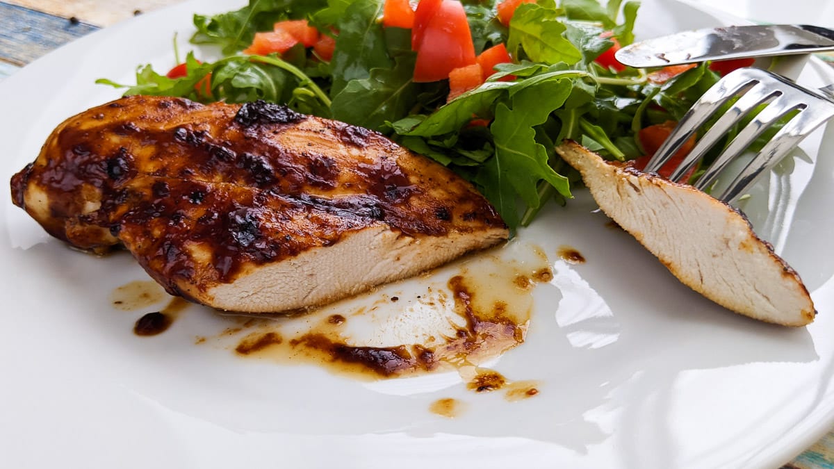 BBQ Chicken breast with salad on white table.