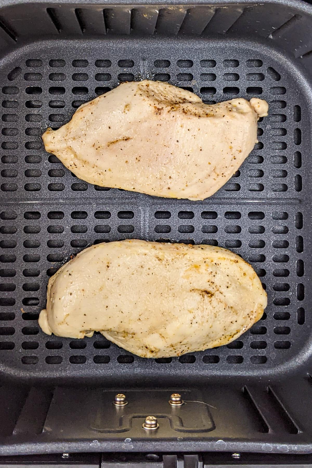 2 Chicken breast pieces in the air fryer basket.