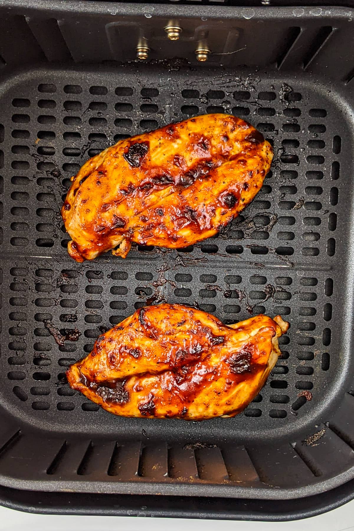 2 pieces of bbq chicken breasts on the air fryer tray.
