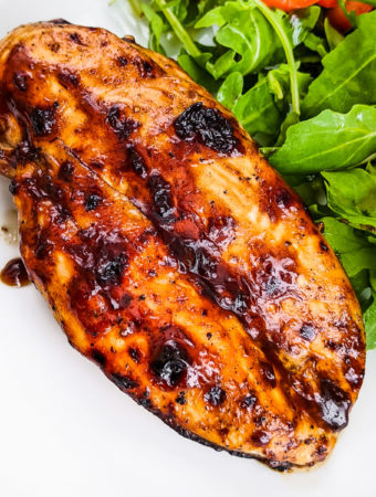 Close look at bbq chicken breast near salad leaves.