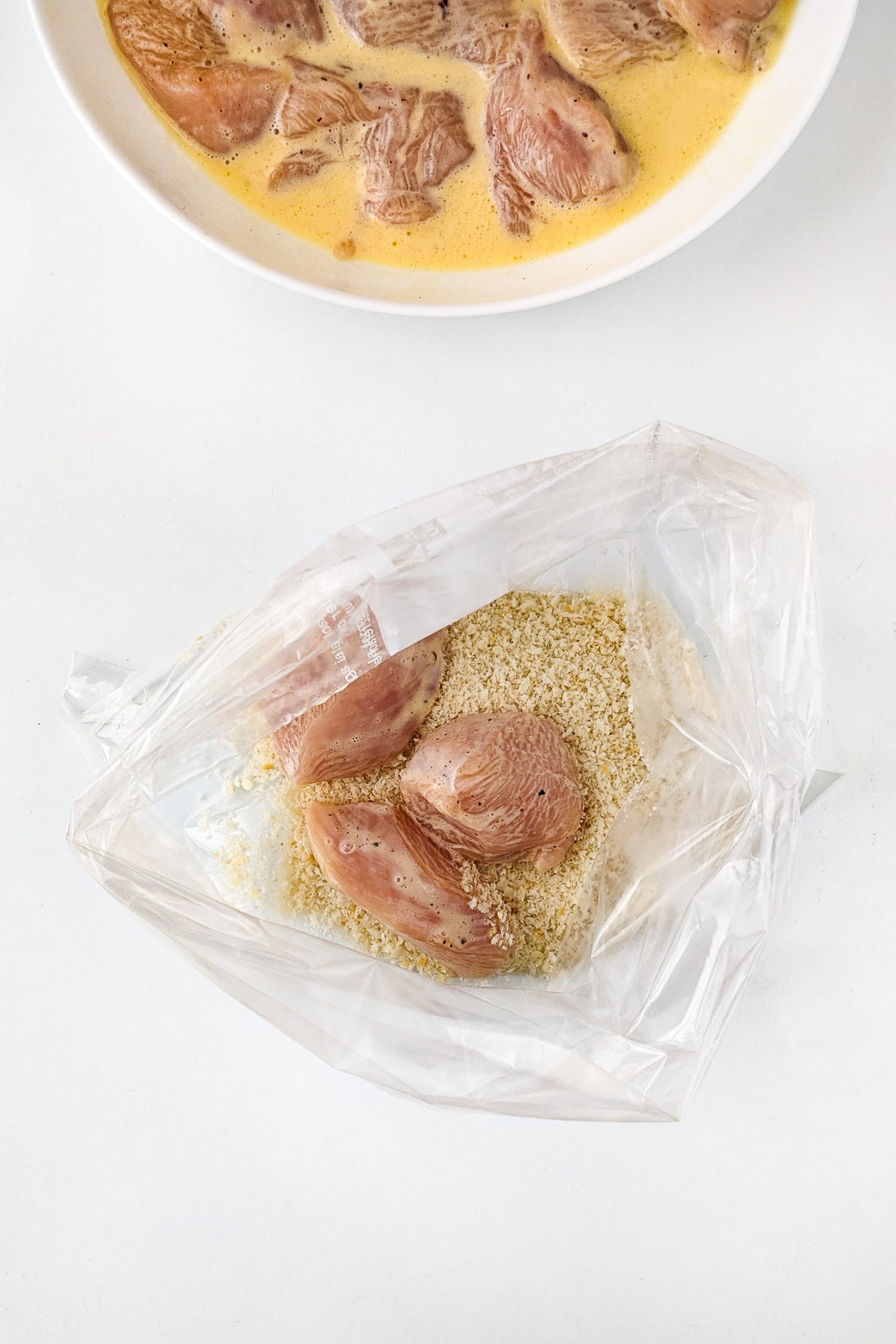 Three pieces of chicken in a plastic bag with panko.