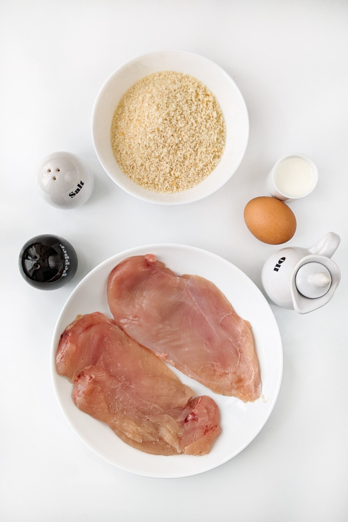 Ingredients for the panko chicken schnitzels in the air fryer on a white table.