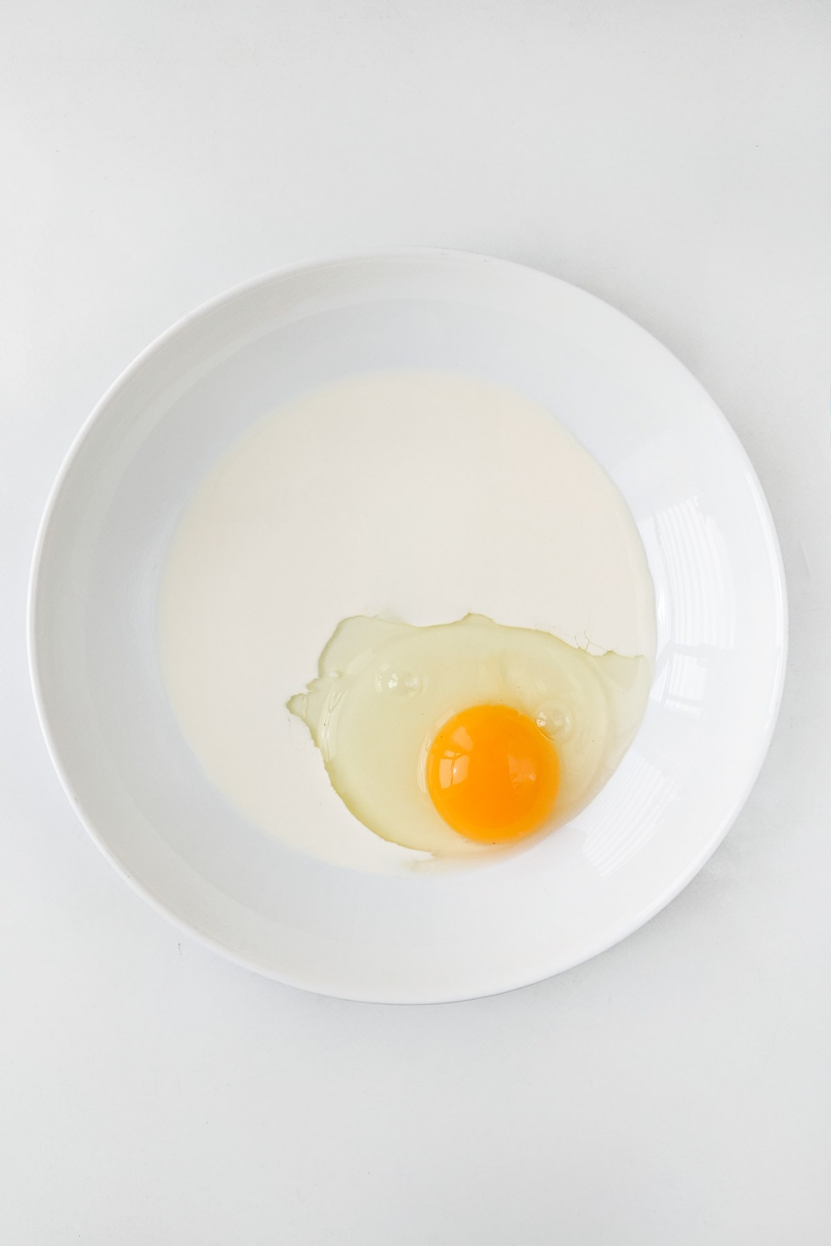White plate with cream and raw egg.