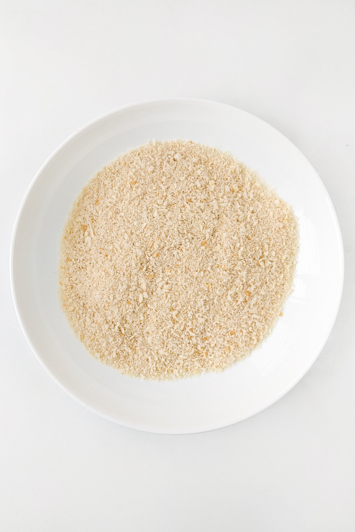White plate with panko on a white table.