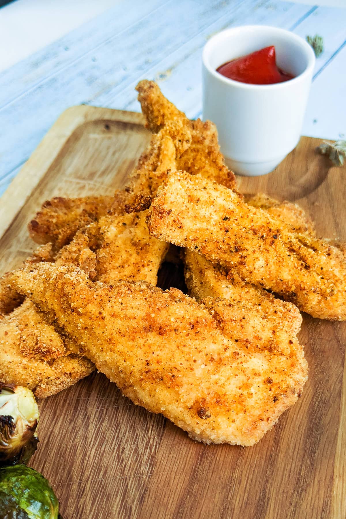 Chicken strips in air fryer made from scratch on a wooding board.
