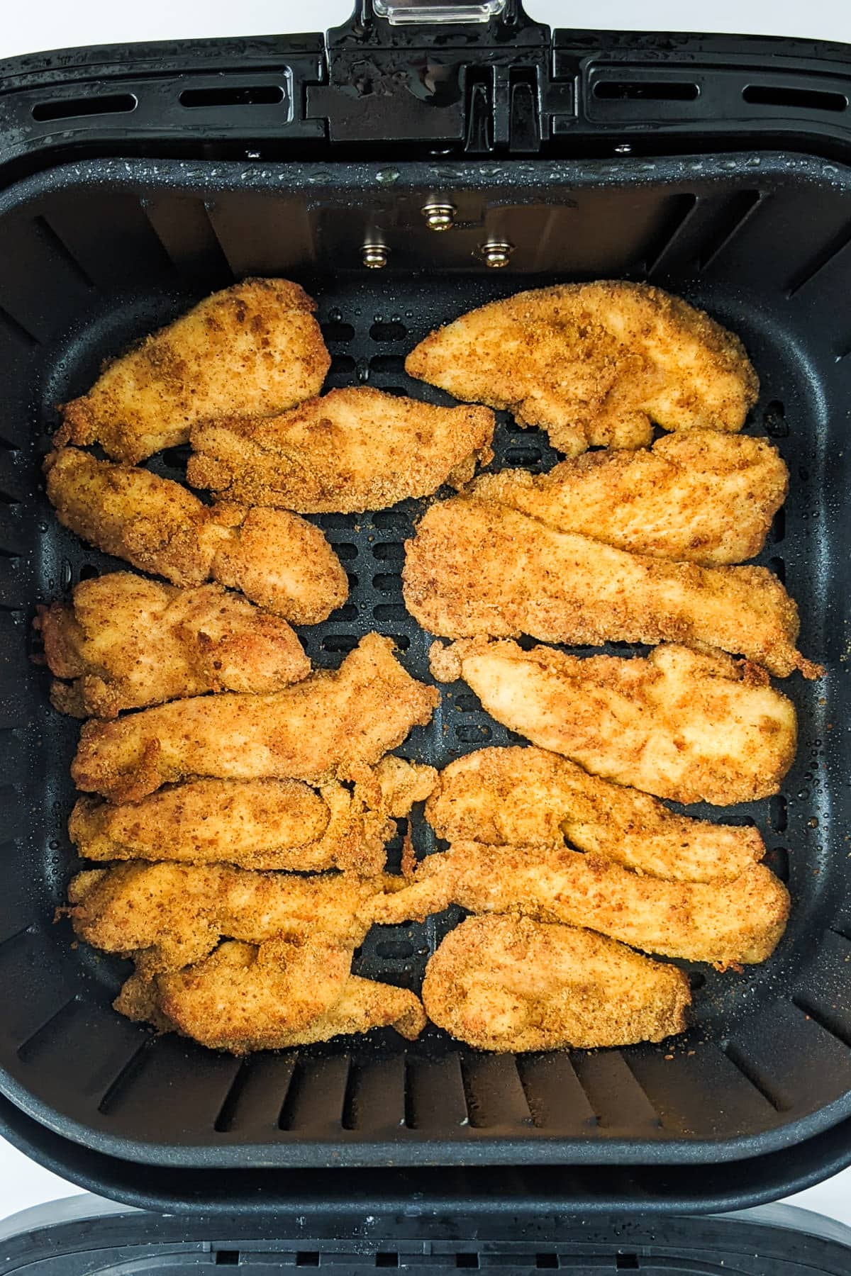 Top view of fried chicken strips in the air fryer basket.