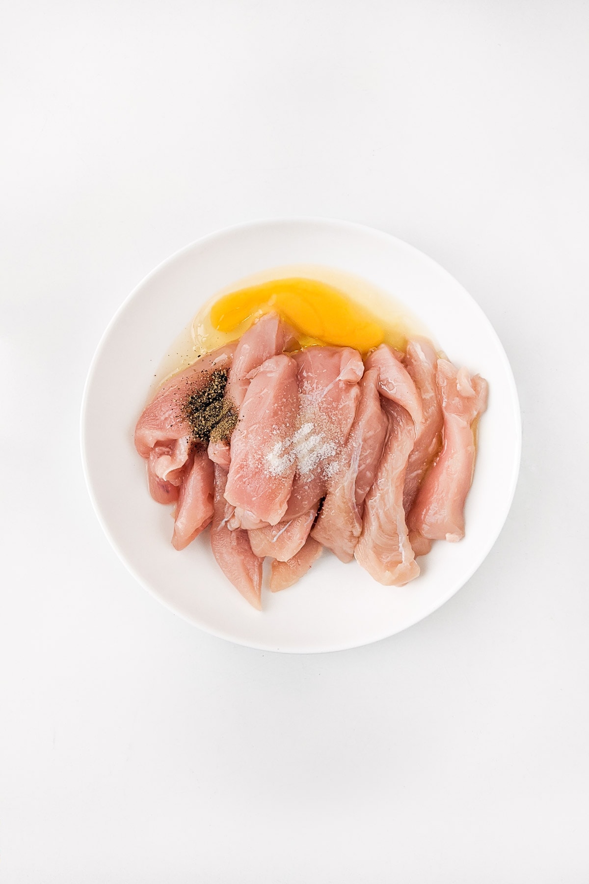 Raw chicken strips with salt, pepper, oil and raw egg.