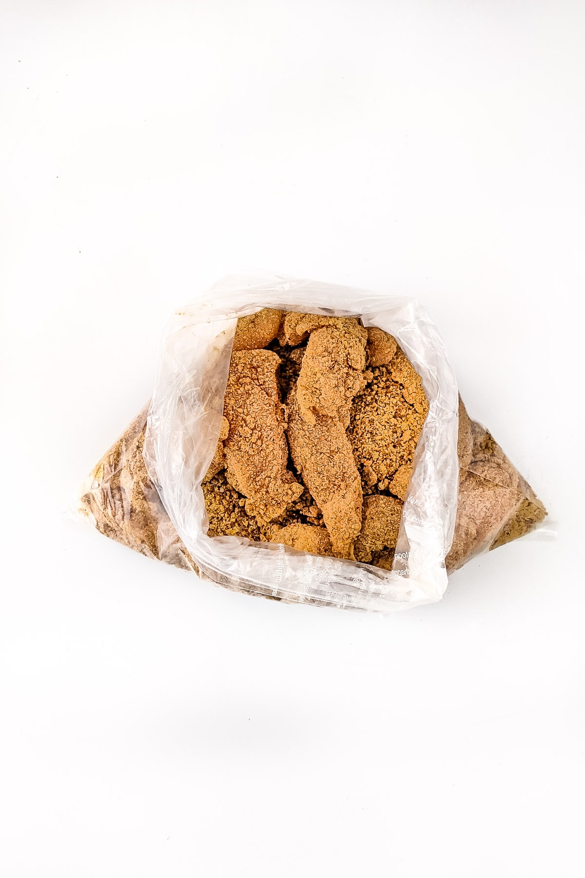 Plastic bag with Chicken strips coated with bread crumbs on all sides.
