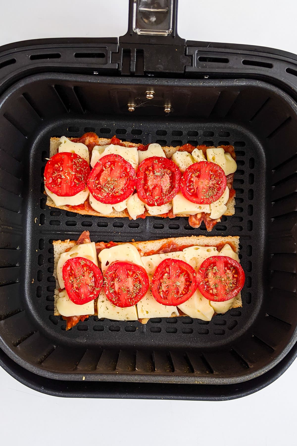 French bread pizza with fresh tomatoes in air fryer basket.