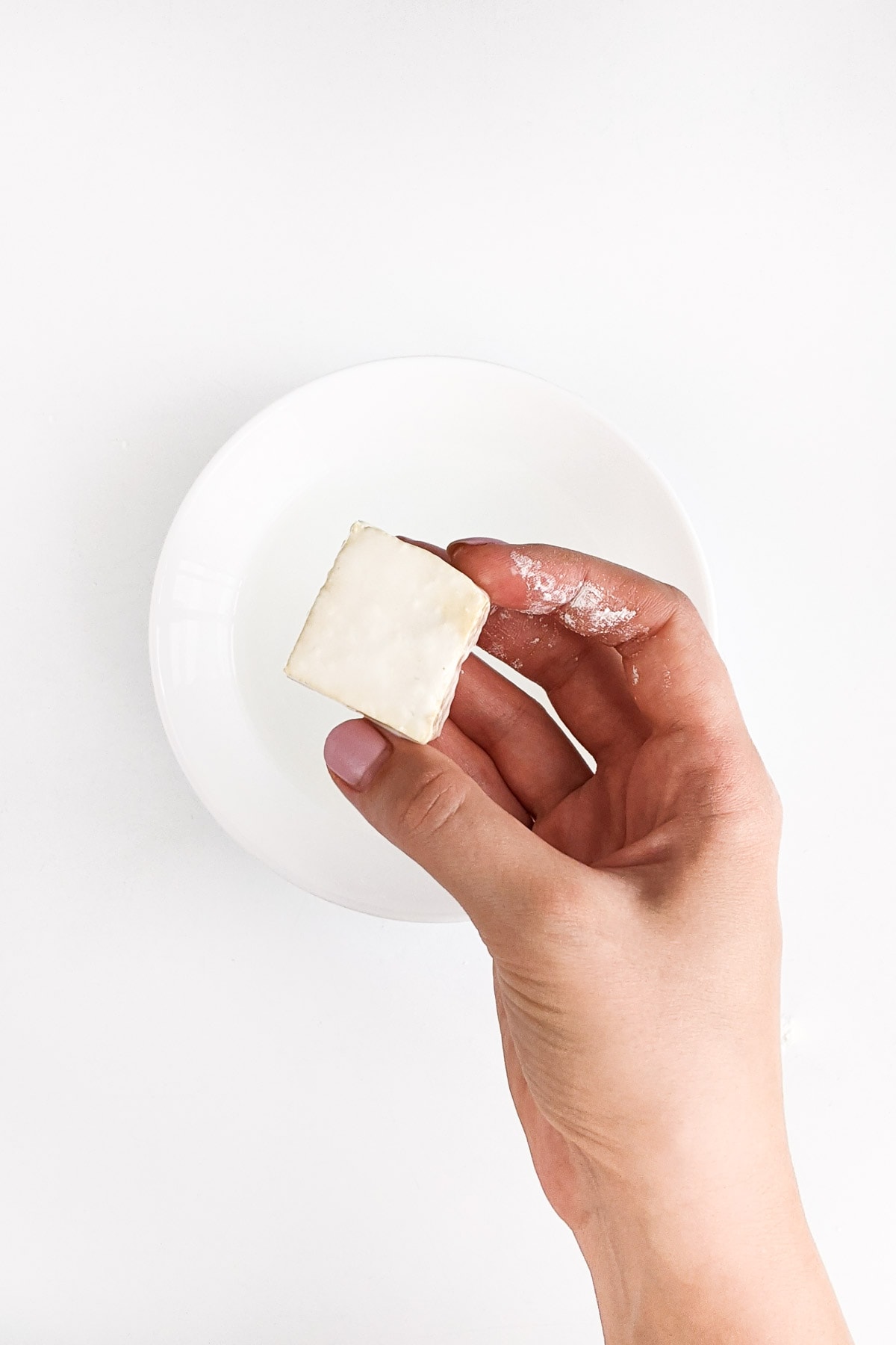 Woman hand holding a piece of tofu.