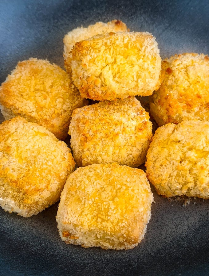 Close look at air fryer tofu nuggets on a dark plate.