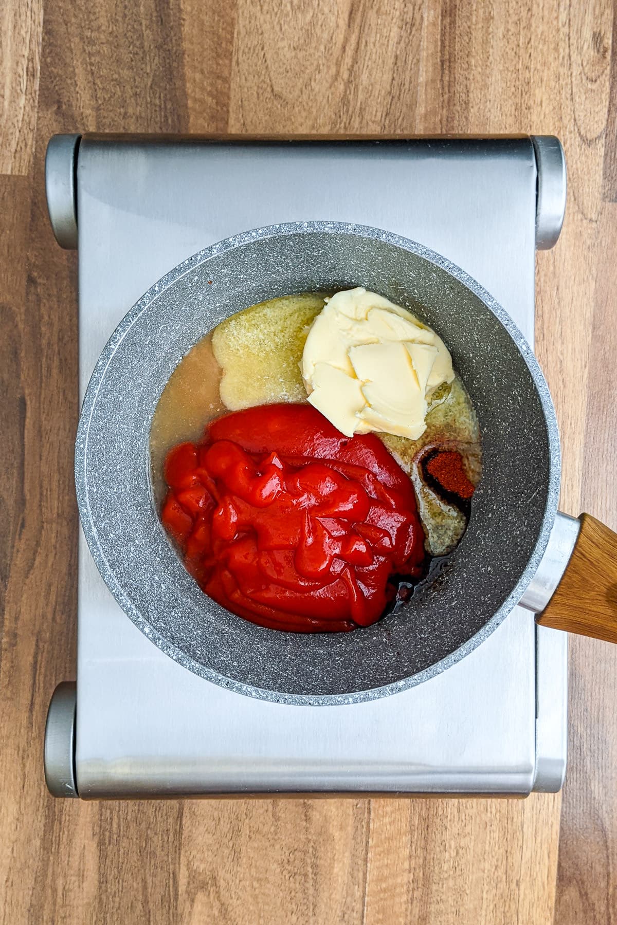 Sauce pan with chili sauce, melted butter and paprika.