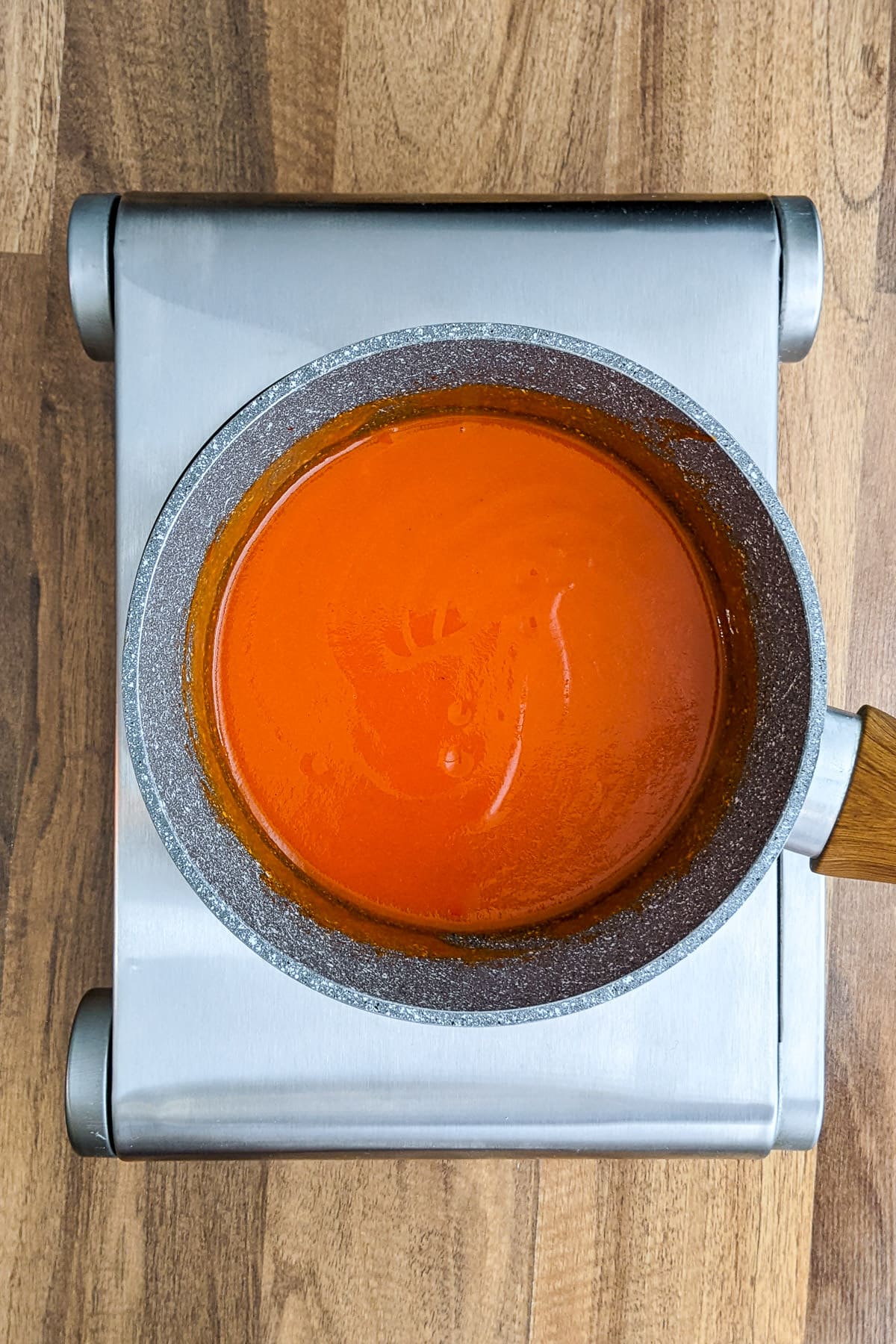 Sauce pan with Homemade Buffalo Sauce on a hob.