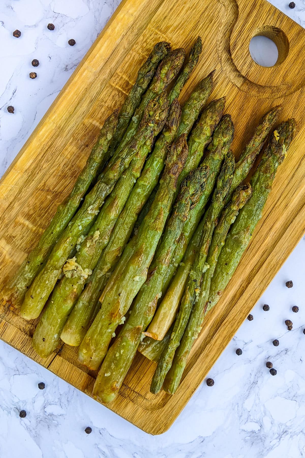 Wooden Cutting board with asparagus roasted in air fryer.