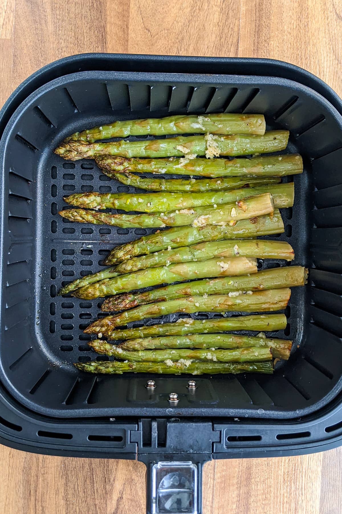 Top view of air fryer basket with roasted asparagus