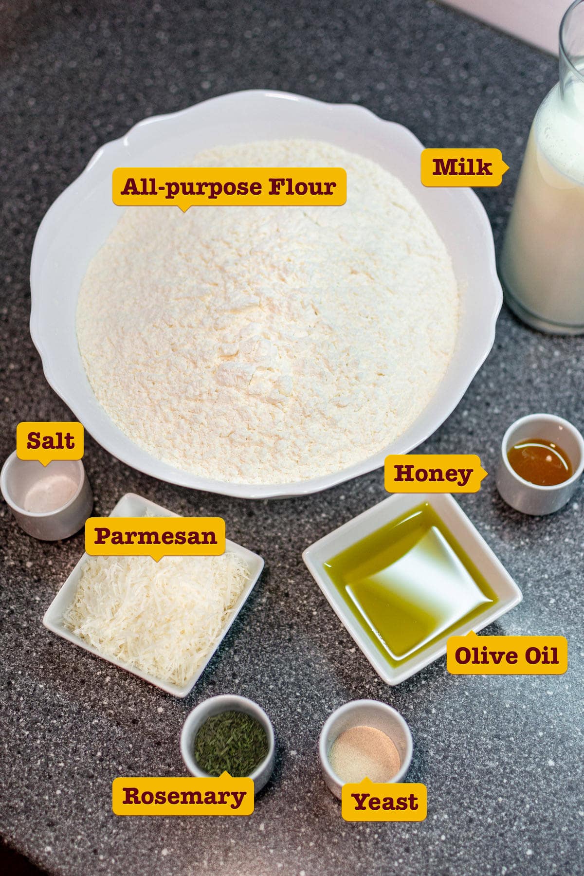 All purpose-flour, parmesan, milk, olive oil on a stone table.