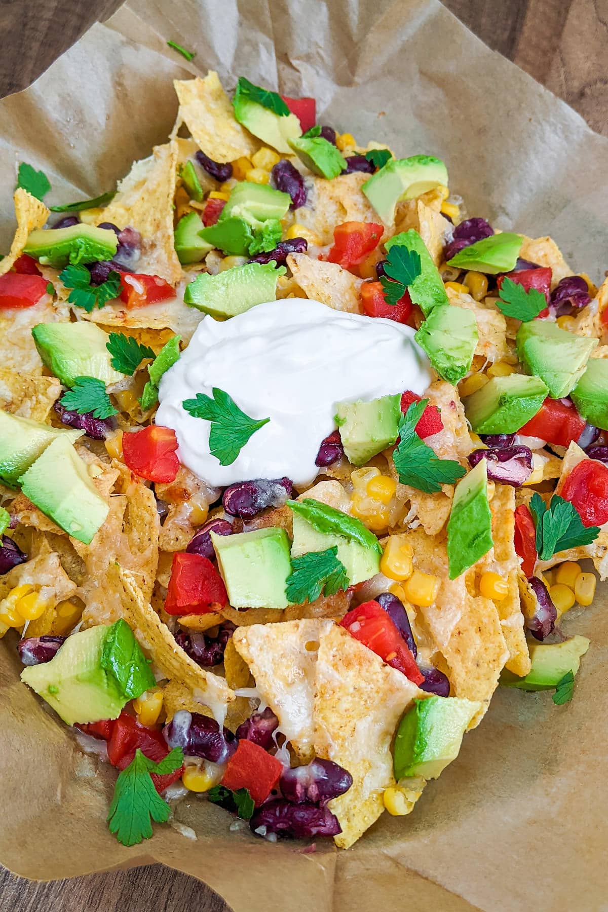Close look of air fryer nachos with chopped parsley, avocado, beans and tomatoes.