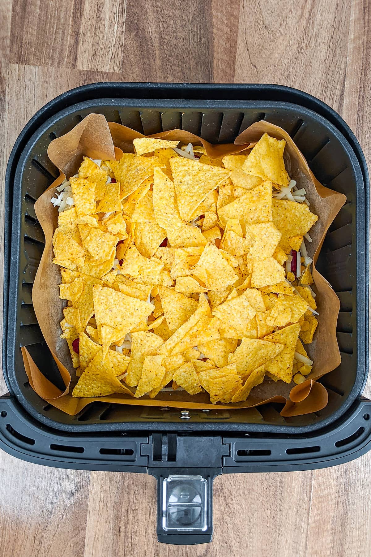 Top view of air fryer basket with tortilla chips.