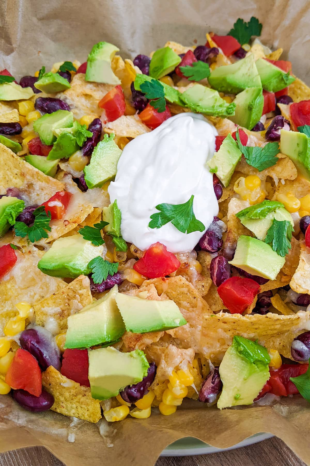 Close look of cheese loaded air fryer nachos on a parchment paper.