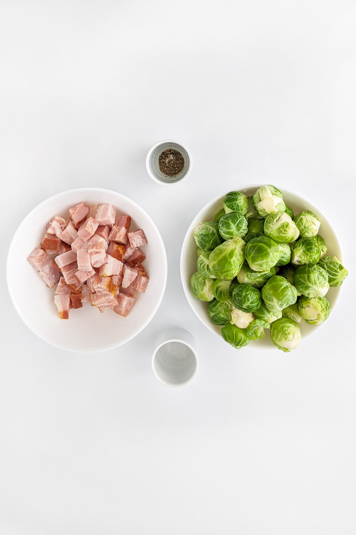 White plates with diced bacon, brussels sprouts, salt and pepper.