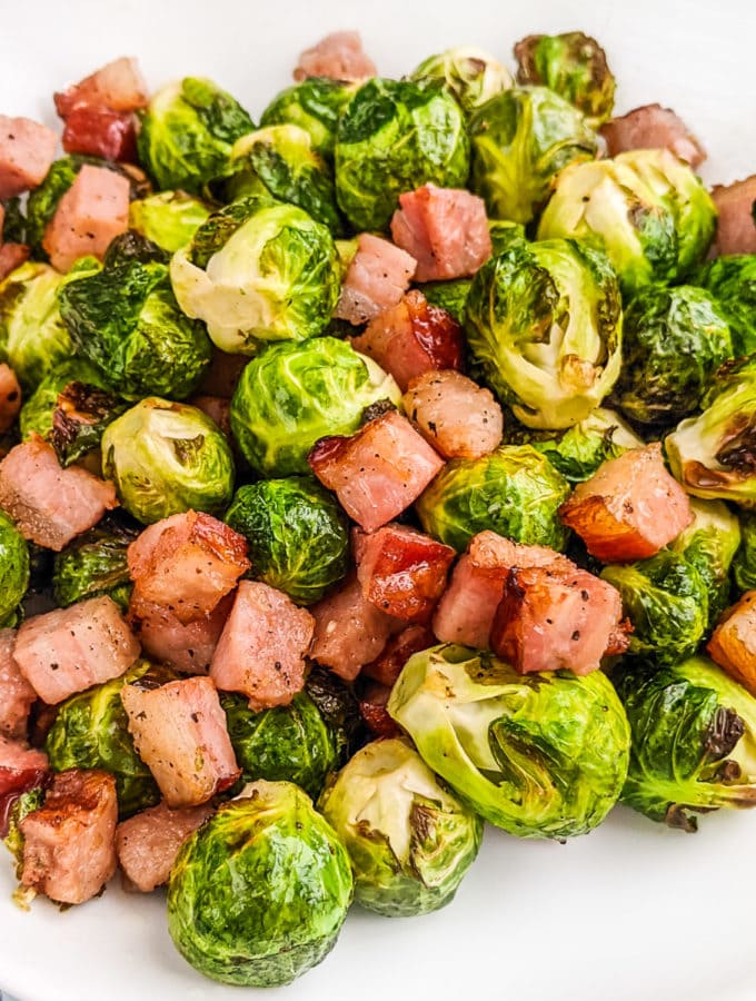 Brussels sprouts with bacon on a white plate.