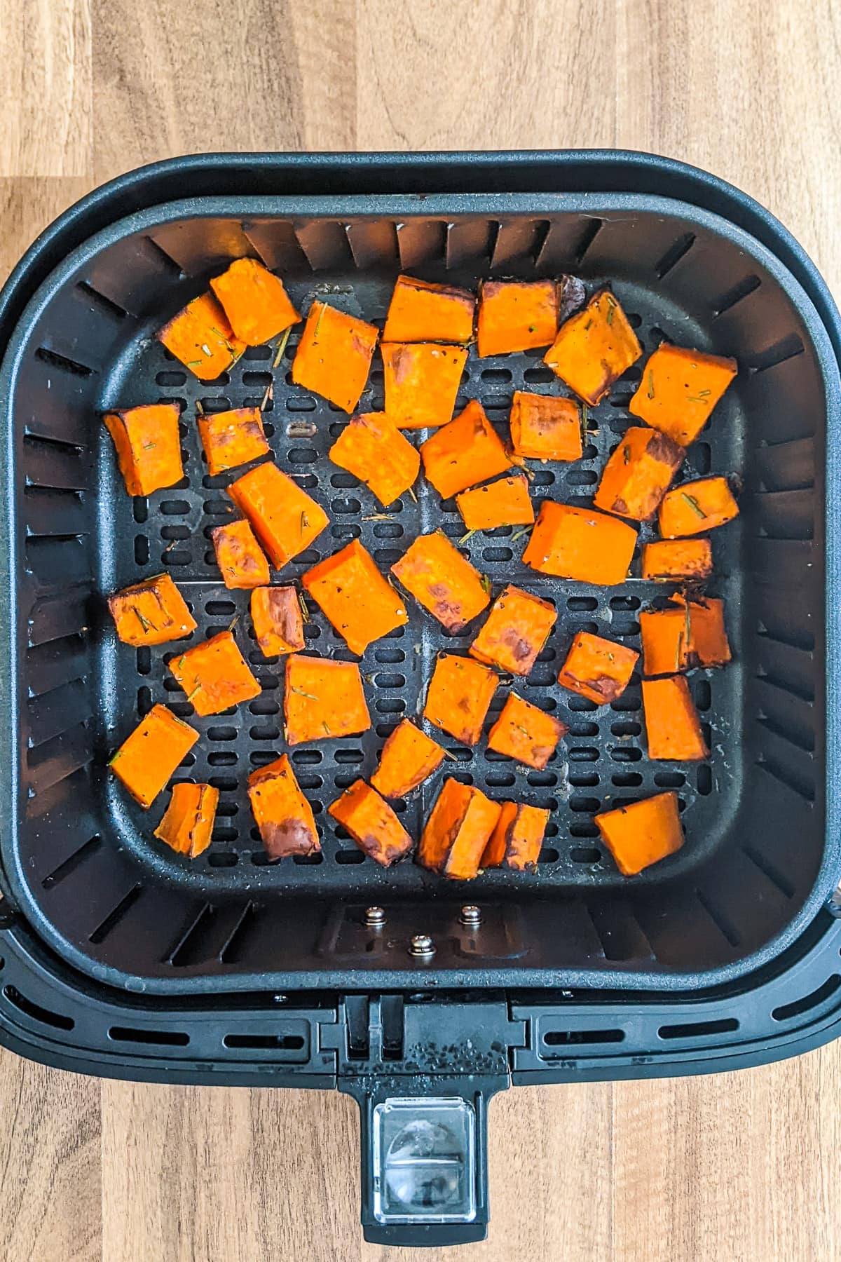 Top view of Roasted Butternut Squash chunks in air fryer basket.