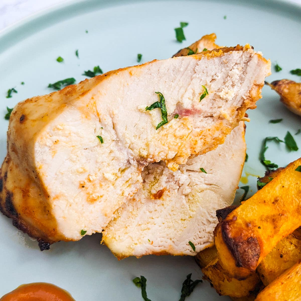 Close look of juicy air fryer chicken breast with potatoes.