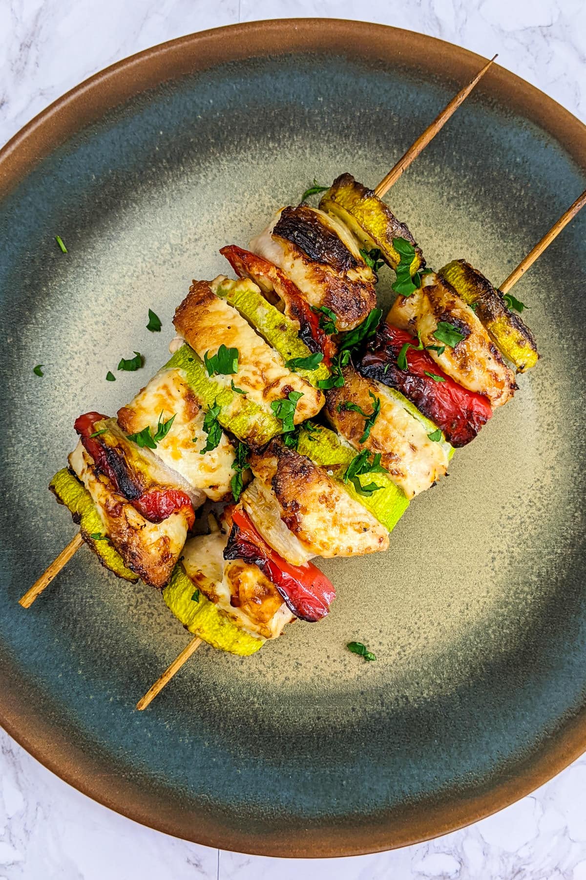 Top view of chicken skewers with diced parsley.