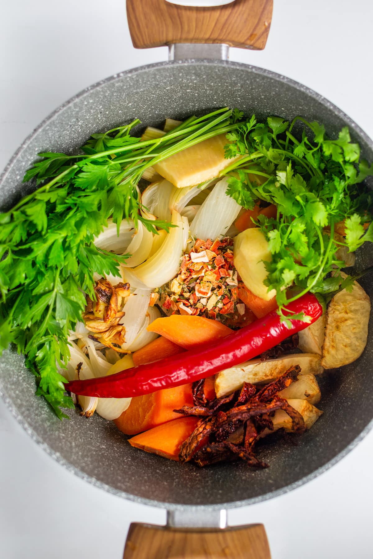 Top view of raw vegetables and spices in a sauce pan.