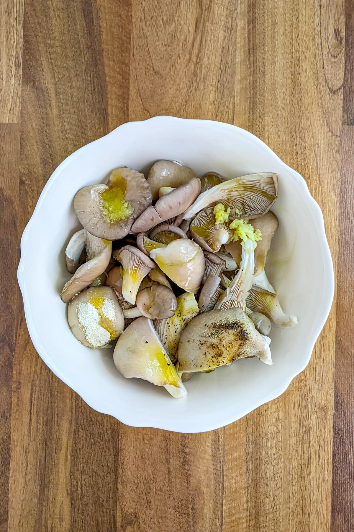 White plate with oyster mushrooms, garlic, oil and salt.