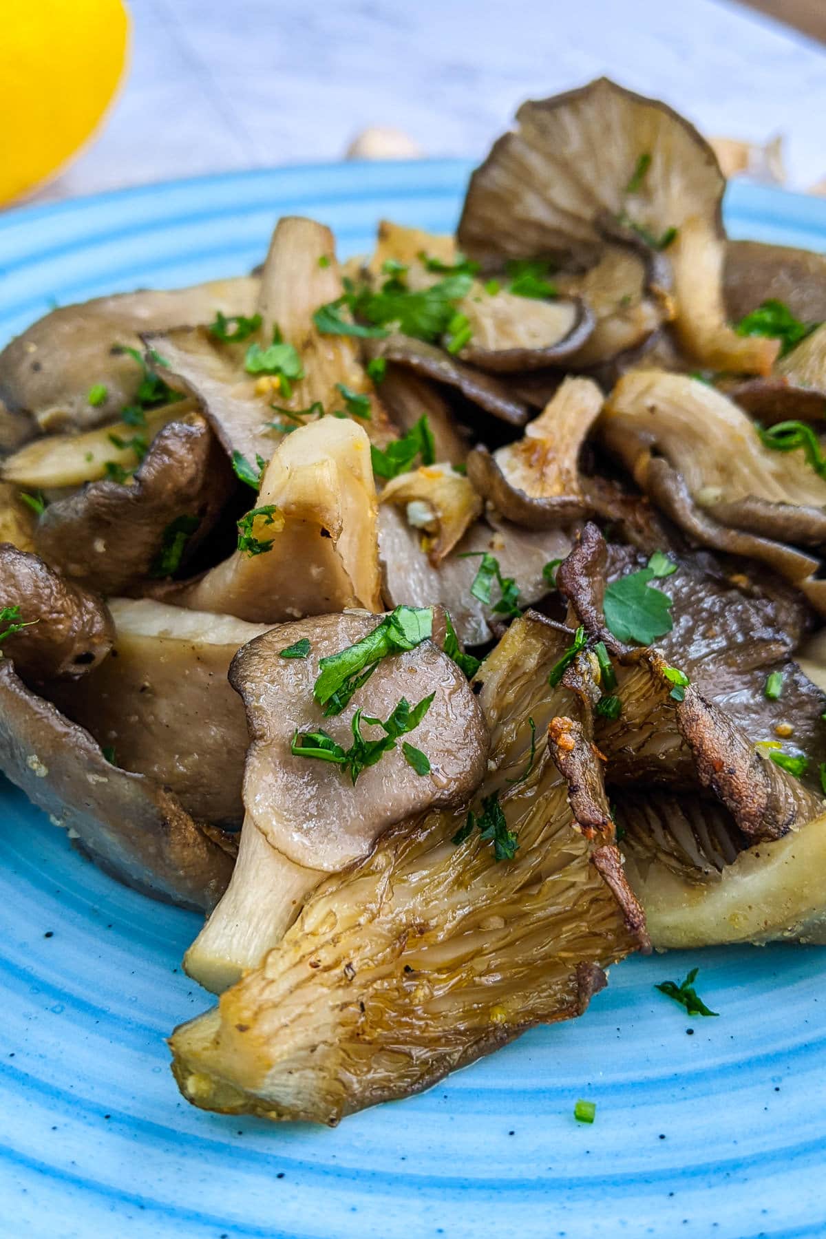 Blue plate with oyster mushrooms with chopped parsley.