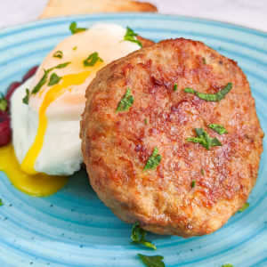 Close look of sausage patties with chopped parsley and egg.