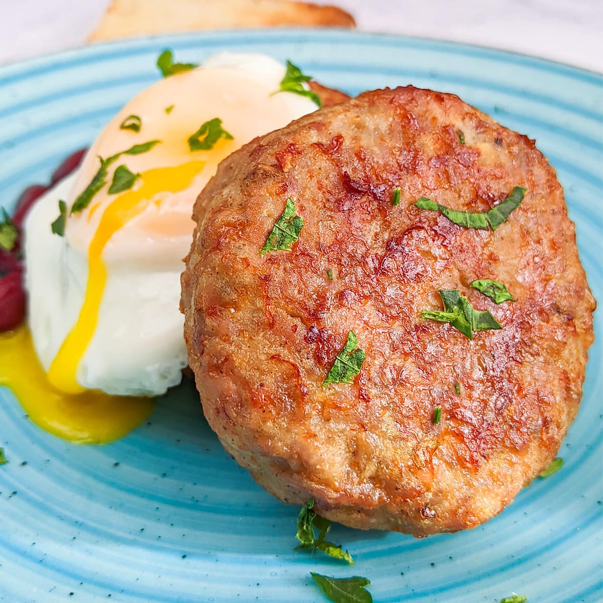 Close look of sausage patties with chopped parsley and egg.