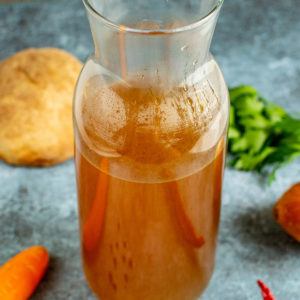 Close view of a transparent bottle with vegetable broth.
