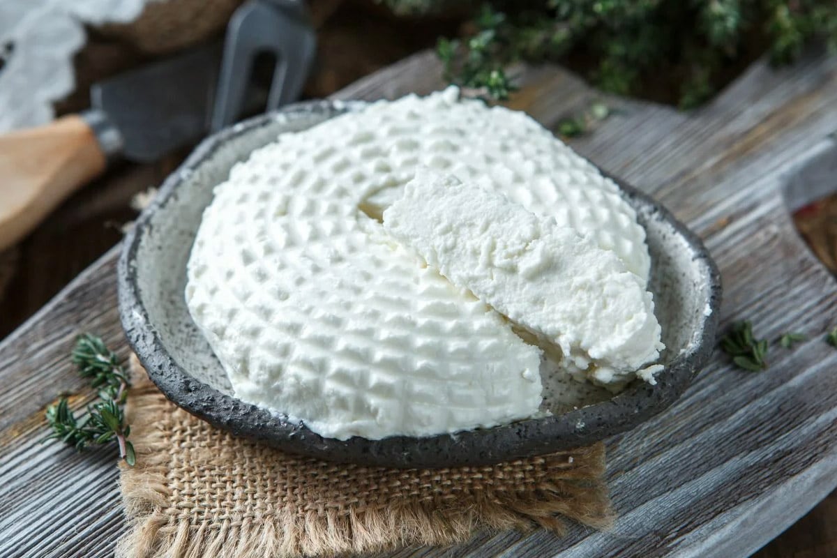 A metal plate with soft goat cheese with a rustic background.