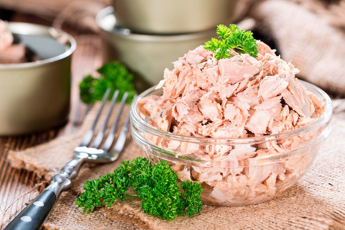 Transparent bowl with canned tuna and parsley.