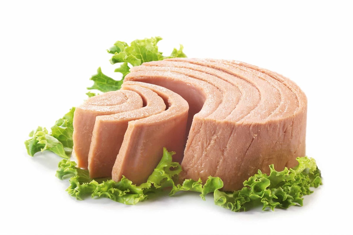 Canned tuna with salad leaves on white background.