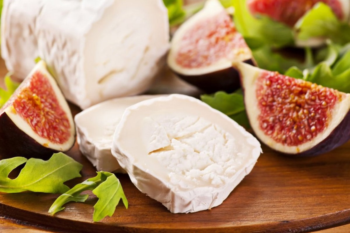 A few slices of goat cheese with figs on wooden table.